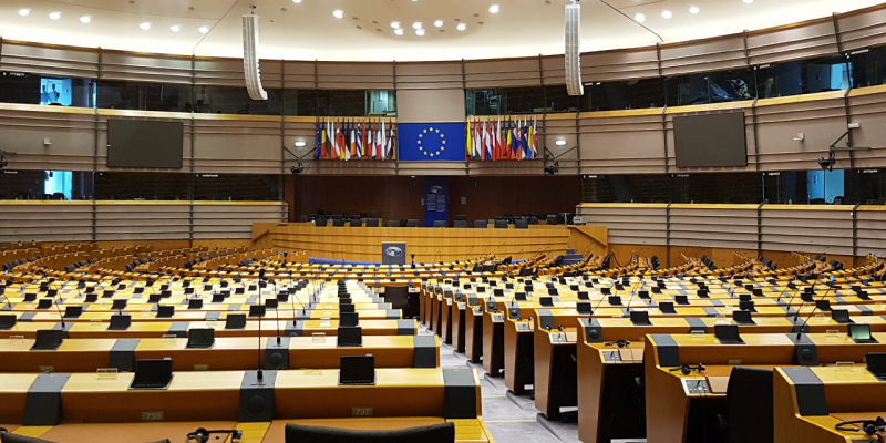 Image of an empty conference room with a large screen and the European flag on it