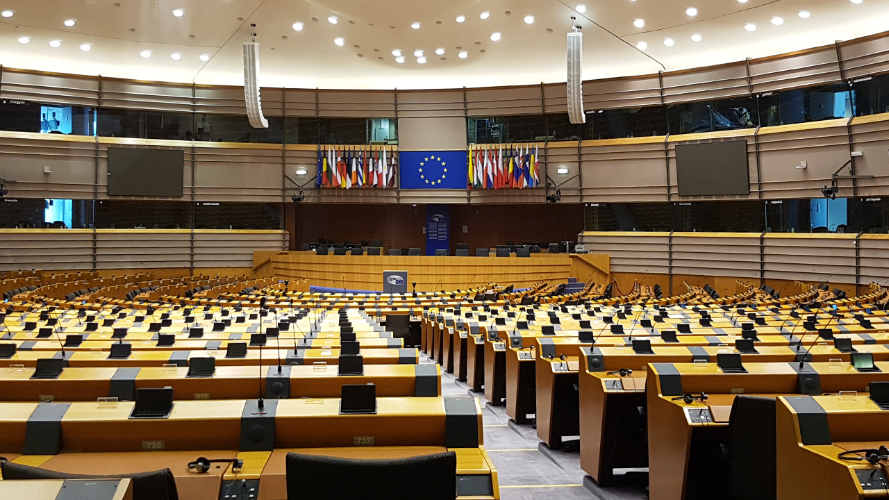 Image of an empty conference room with a large screen and the European flag on it